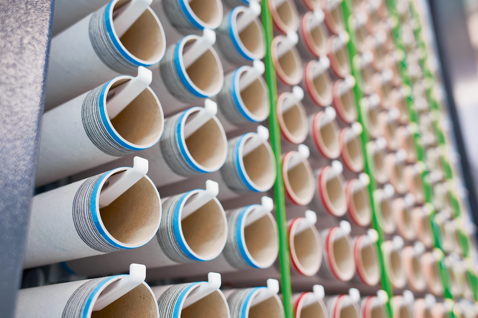 Nahaufnahme des Maschinenkopfs der Rotorspinn-Maschine Autocoro 11 mit dem Fokus auf digital signierte Papphülsen für die individuelle Identifikation produzierter Garne