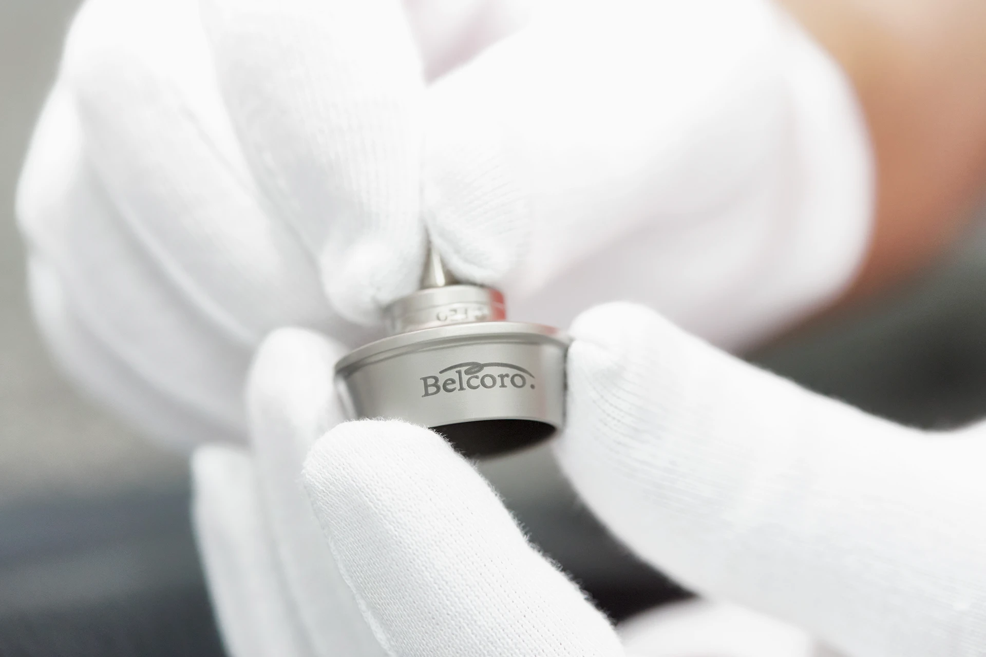 Hand mit weißem Handschuh einen Belcoro Spinnrotor haltend